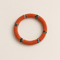 Orange circular beaded bangle with small multicoloured accents.