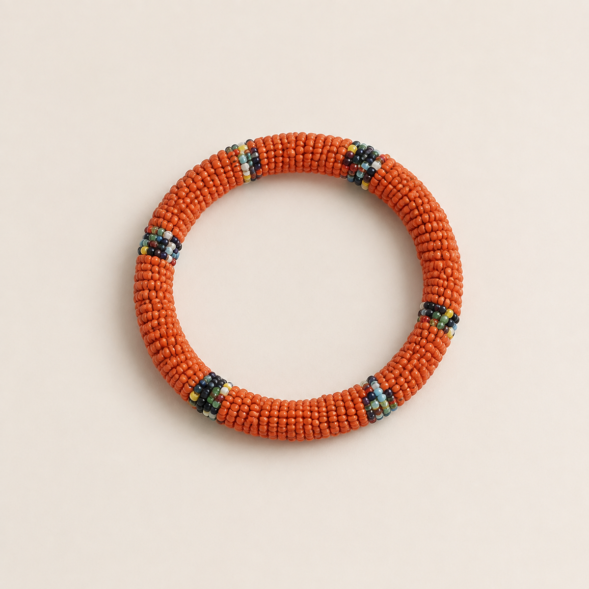 Orange circular beaded bangle with small multicoloured accents.