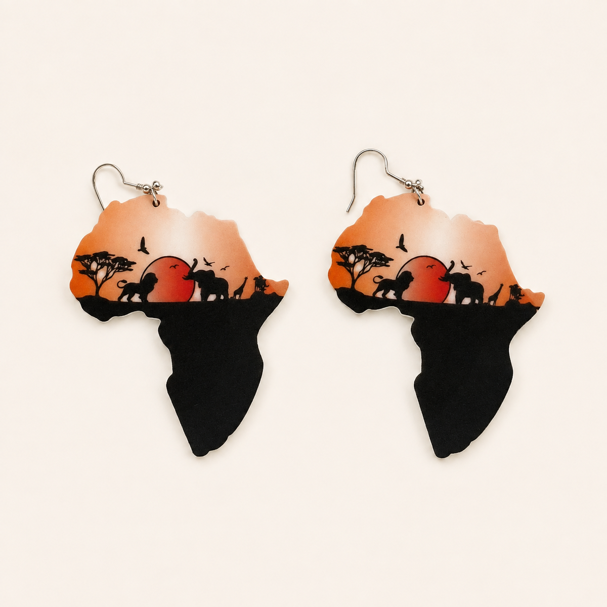 Pair of Africa-shaped wooden earrings with orange-red sunset artwork and dark landscape silhouettes.