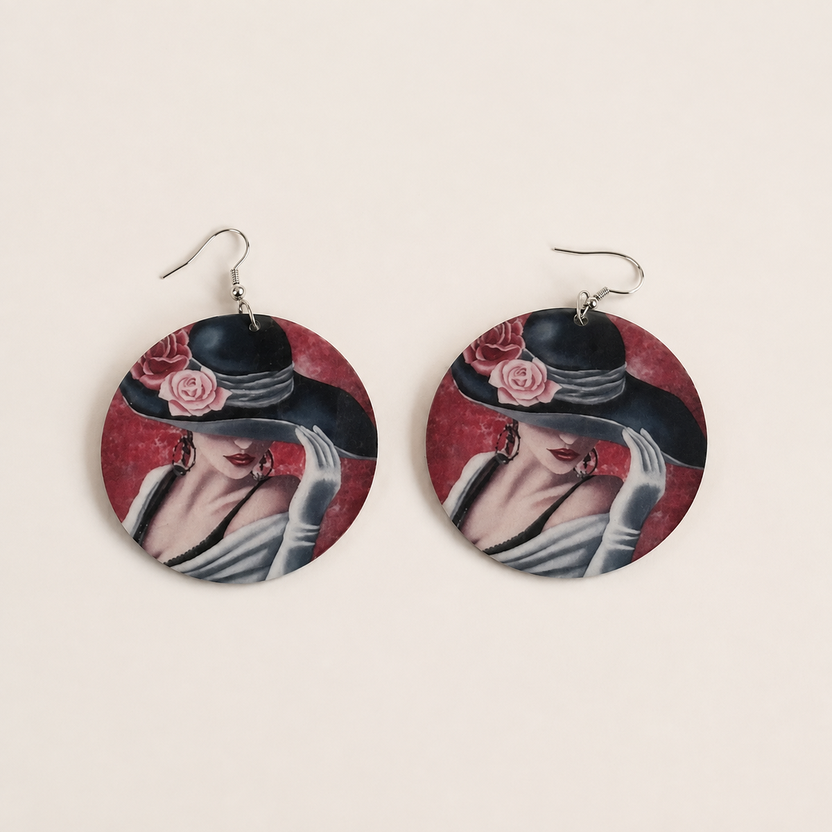 Pair of round wooden drop earrings showing a woman wearing a floral hat against a red background.