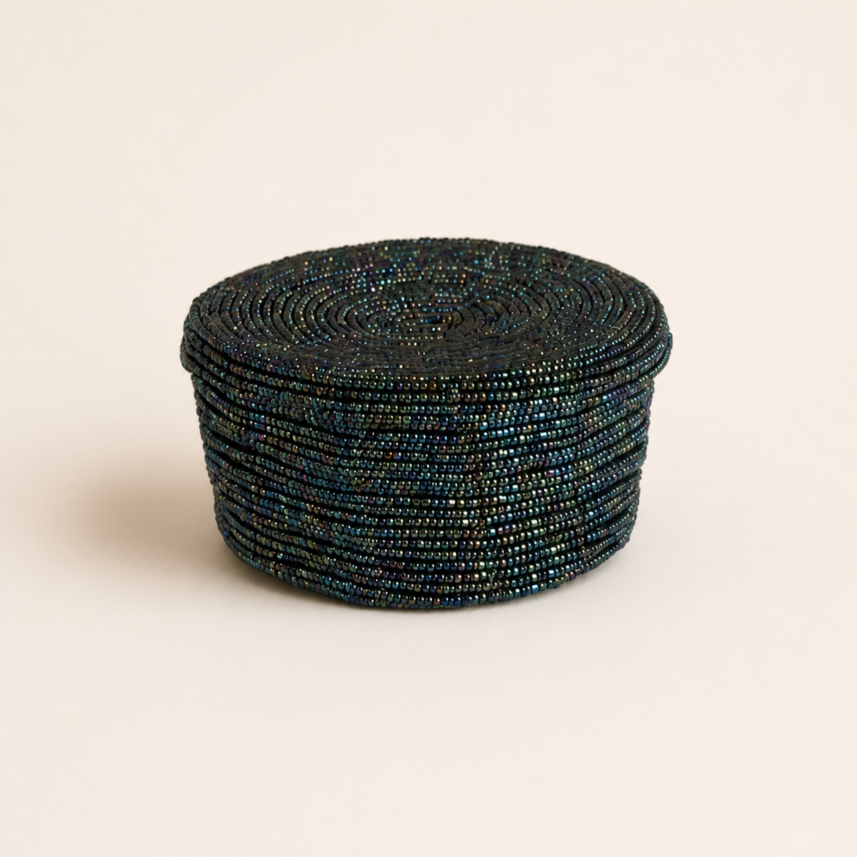 Dark teal round hand-beaded storage box.