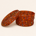 Burnt orange hand-beaded storage box with multicoloured geometric accents and an open lid.